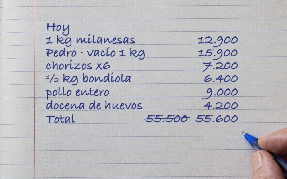 Hoja de cuaderno con las ventas escritas a mano y el total corregido
